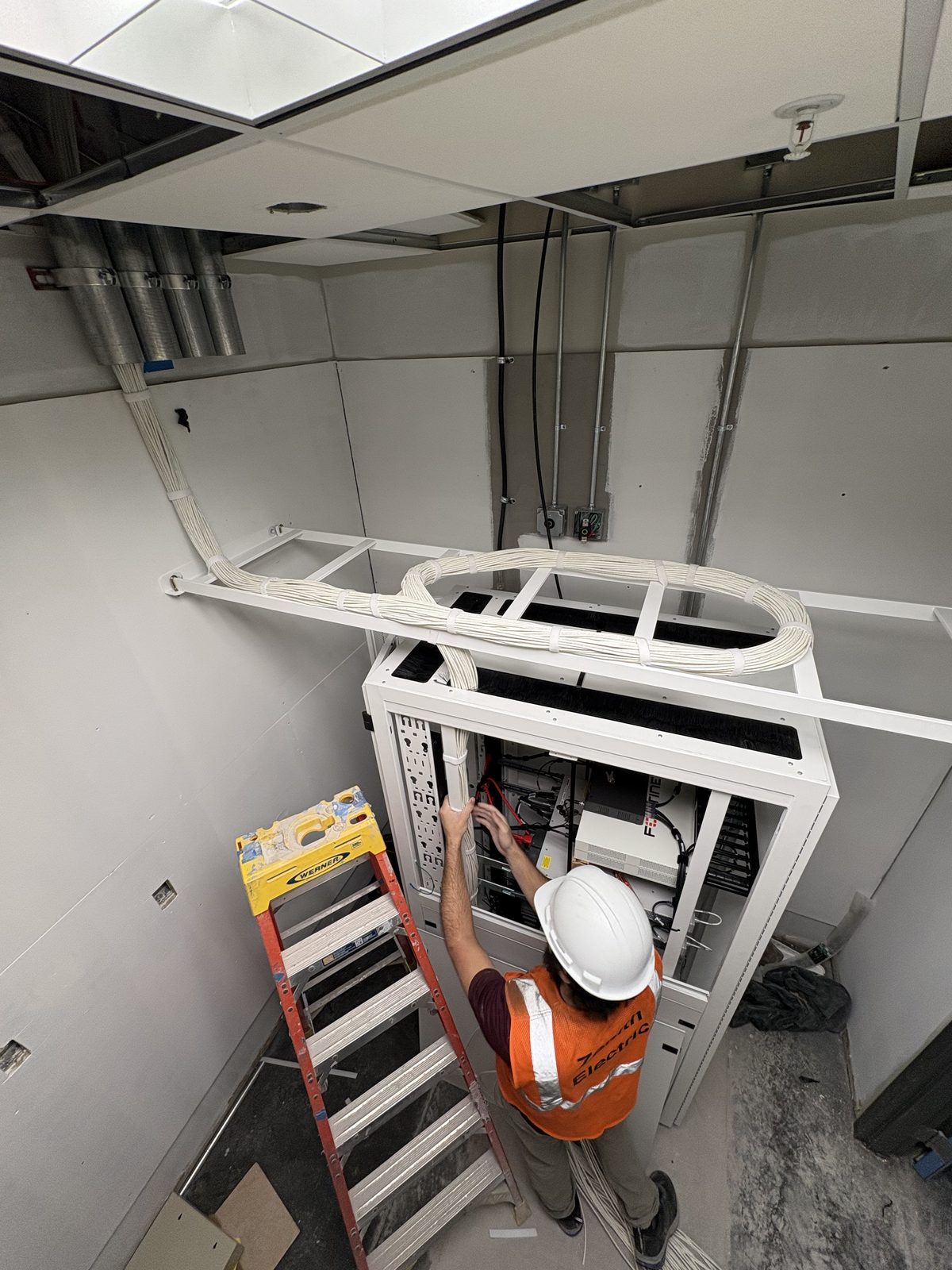 Technician dressing a service loop at a wall-mounted rack