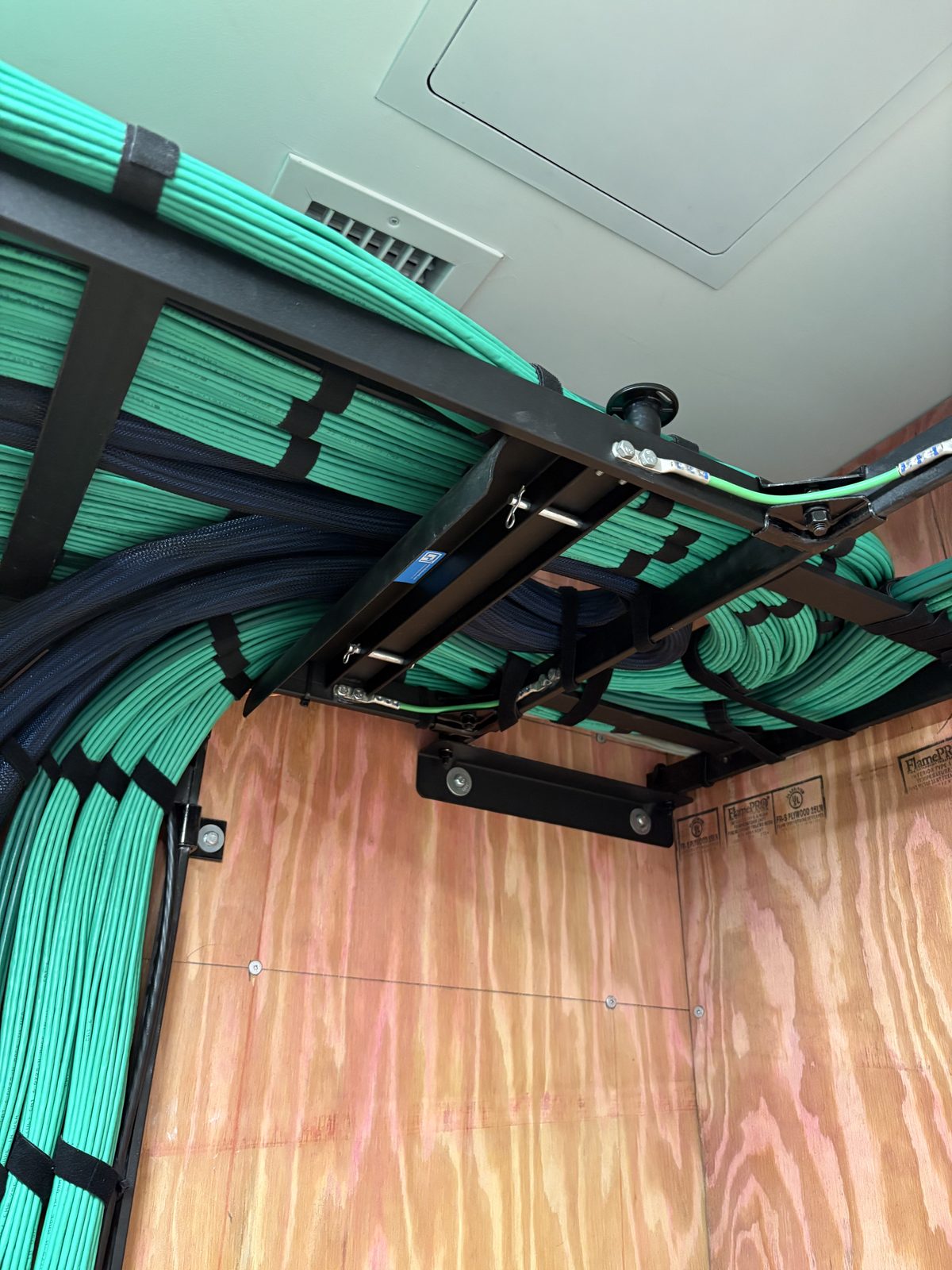 Combed green Cat6 bundles on a ladder rack, close detail