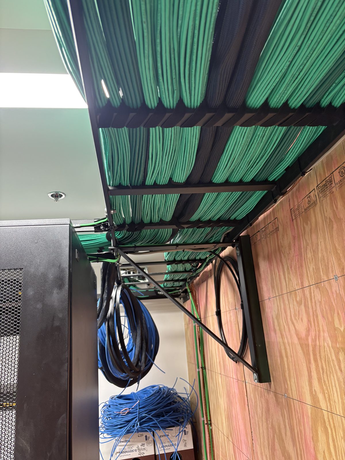 Overhead green Cat6 bundles with cable spools staged below