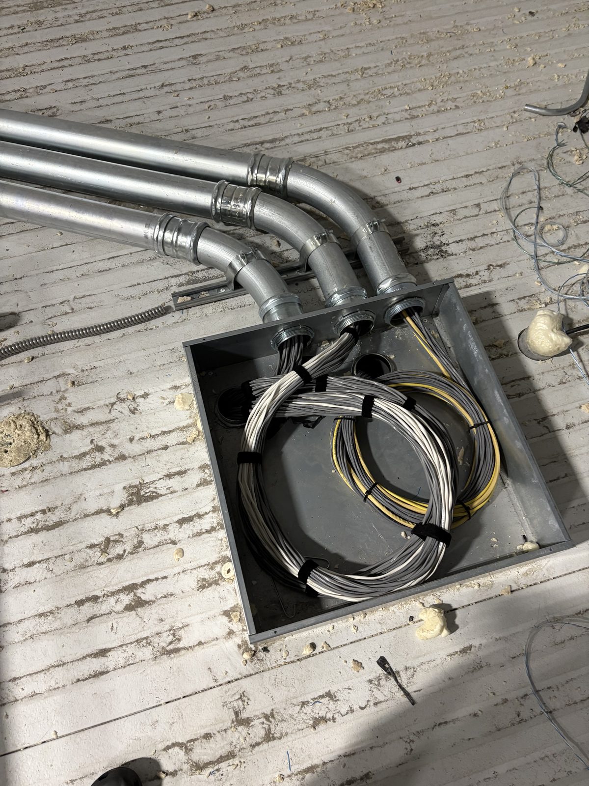 Conduit stub-ups landing in a pull box with coiled service loops