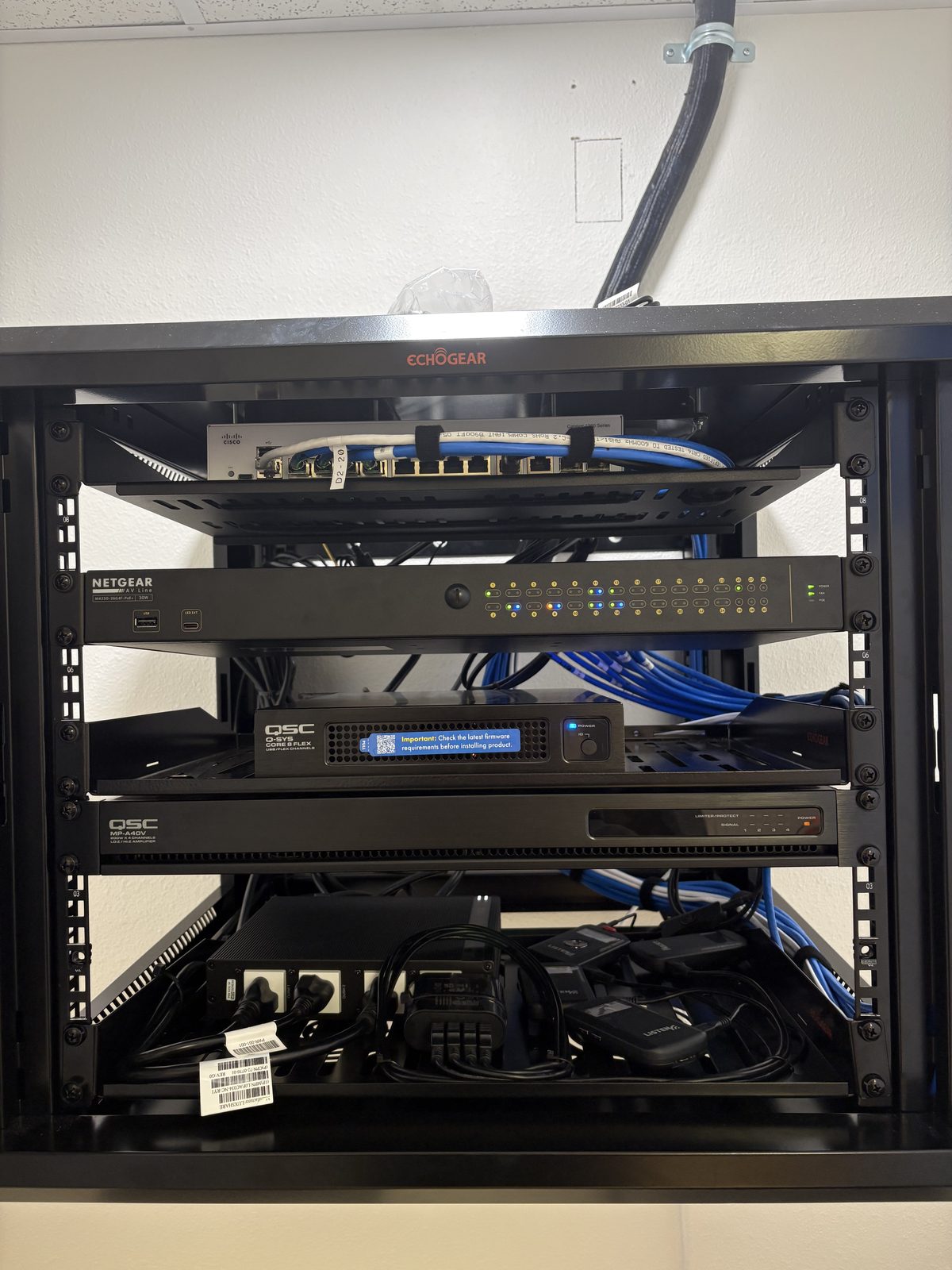 AV equipment rack with Cisco switch, Netgear AV, and QSC Q-SYS