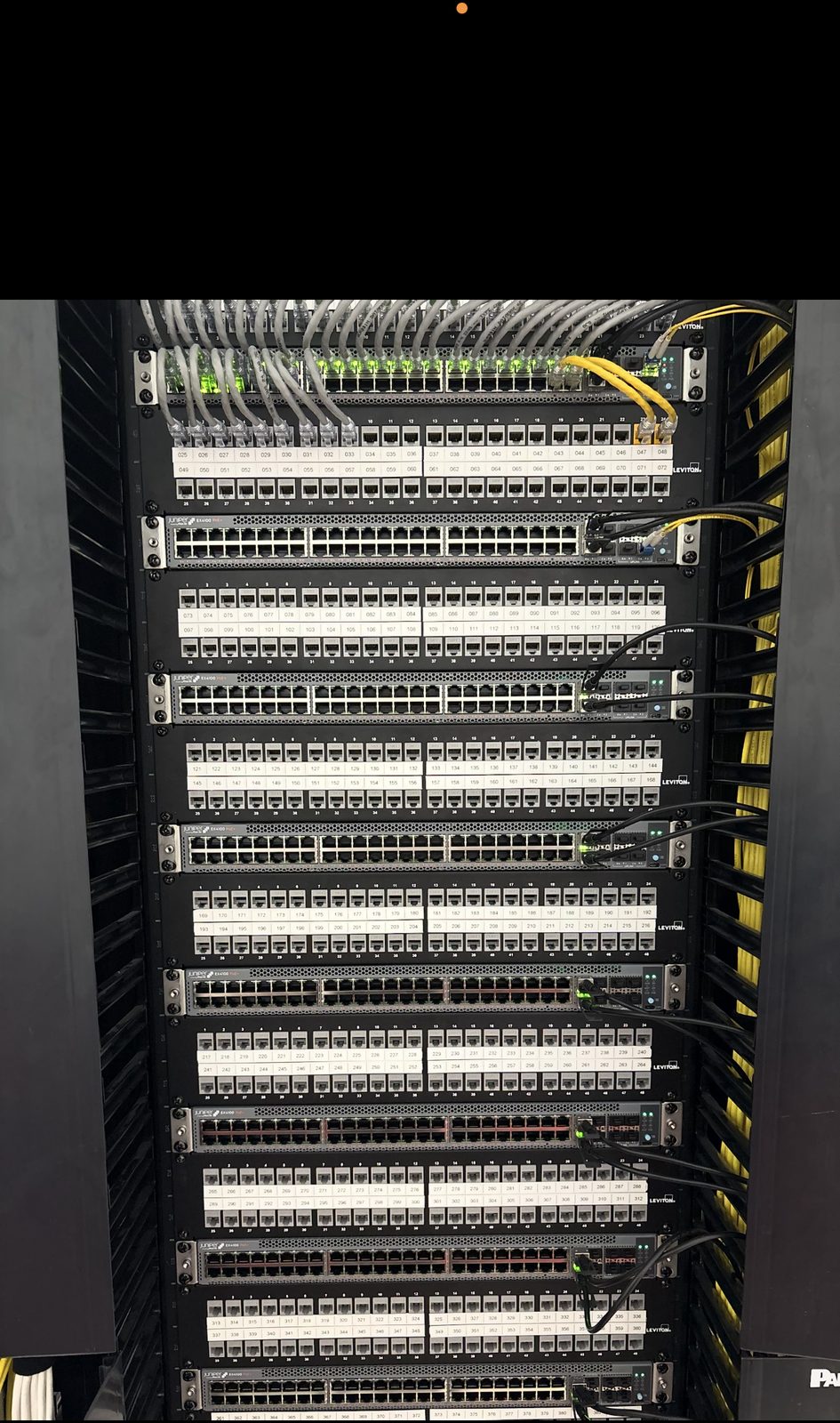 Full-height Juniper EX4100 switch stack with labeled Leviton patch panels