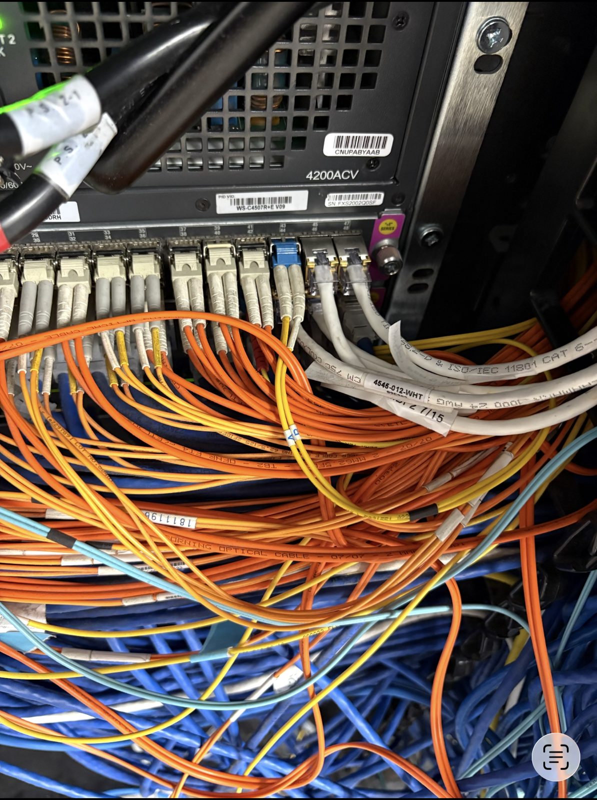 Loose fiber and copper jumpers piled over a chassis switch