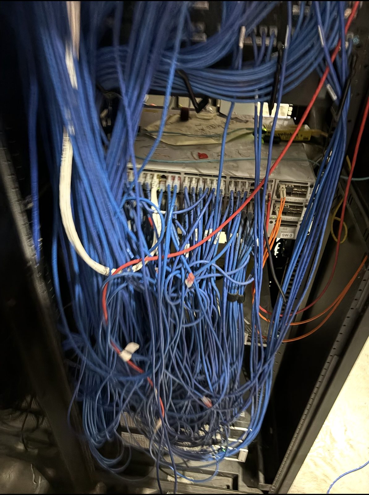 Dense rats-nest of unmanaged blue patch cables at a switch
