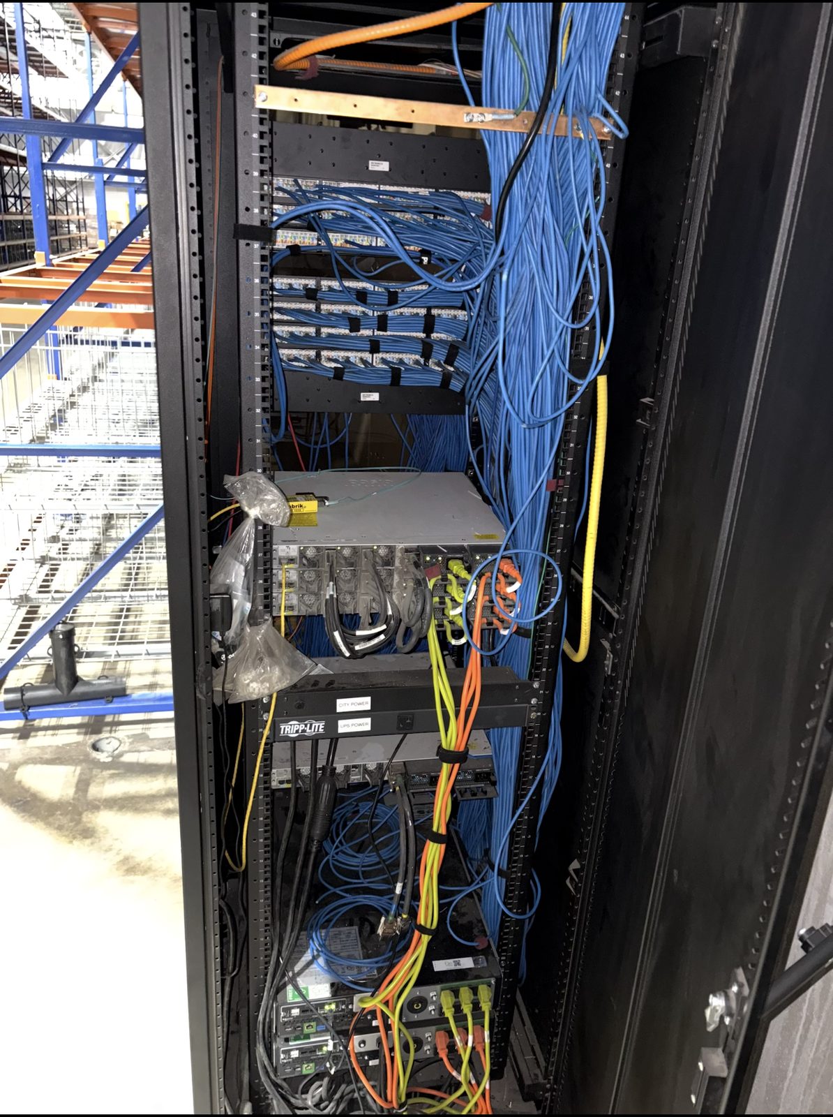 Tall rack overrun with tangled, unsupported blue cabling