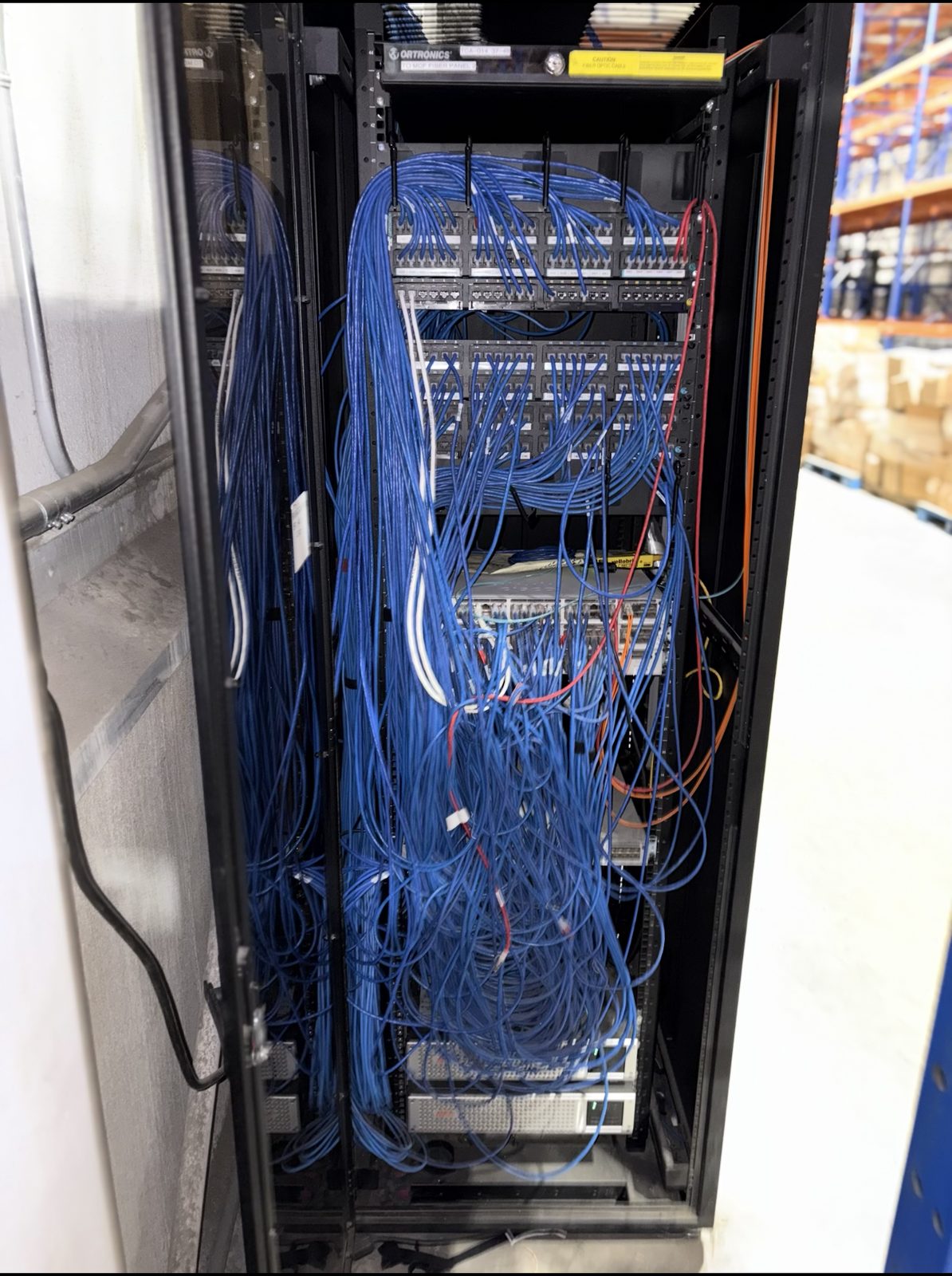 Fiber distribution panel buried under a waterfall of loose blue cable