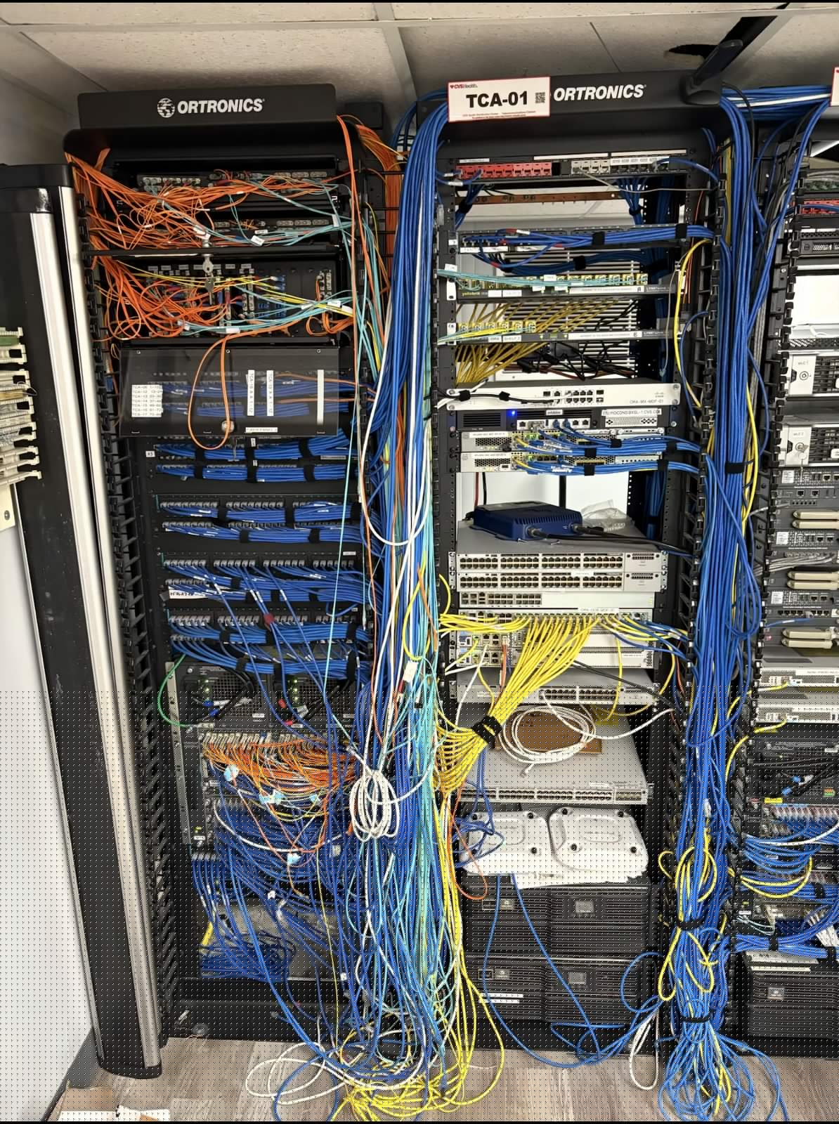 Floor-to-ceiling cable chaos across a labeled distribution rack