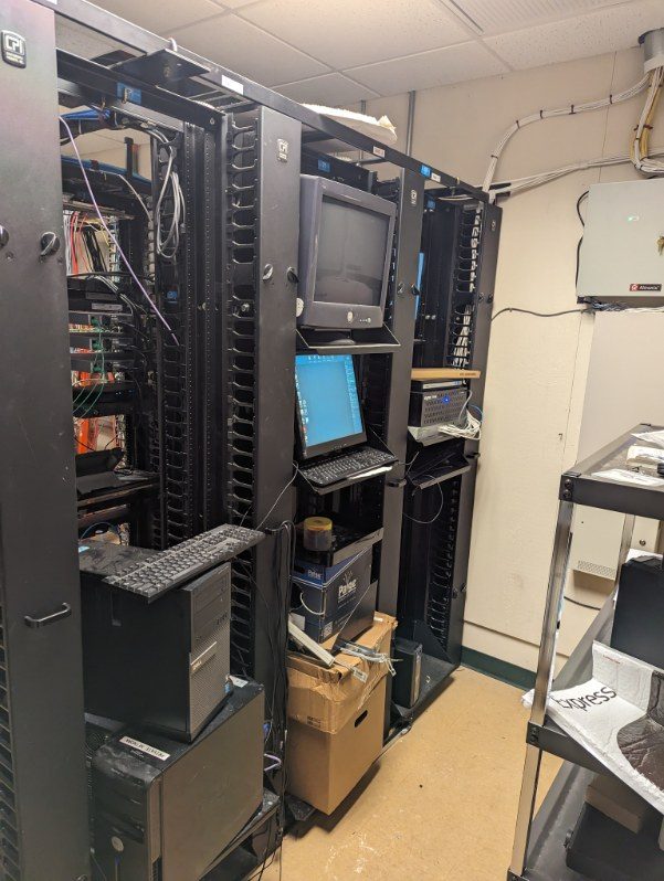 Aging racks with a CRT monitor and equipment stacked on the floor